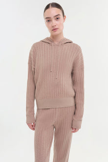 Beige cable knit hoodie with drawstring worn with matching ribbed pants.