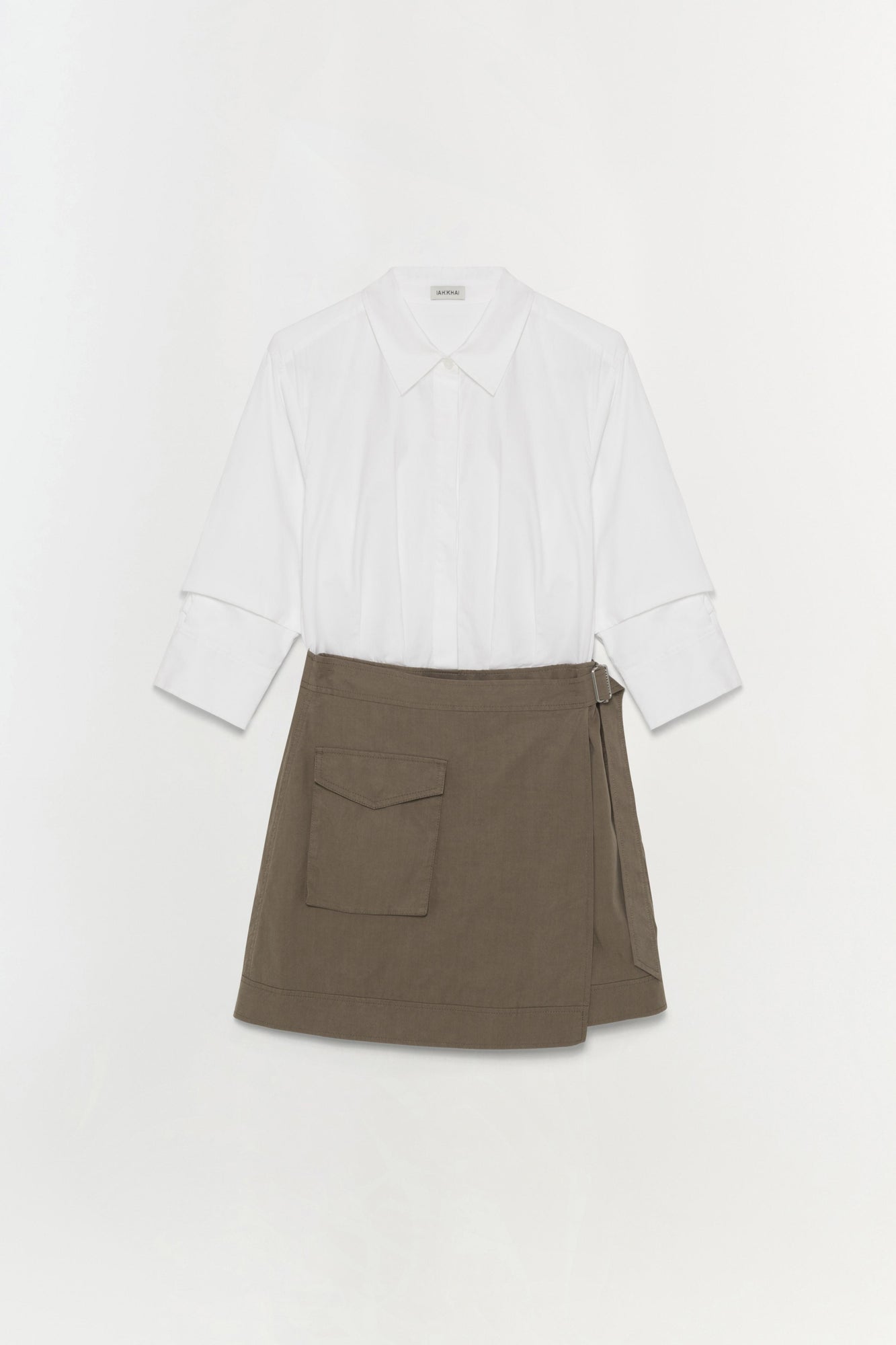 White collared shirt with rolled cuffs paired with olive-brown wrap skirt featuring a patch pocket.