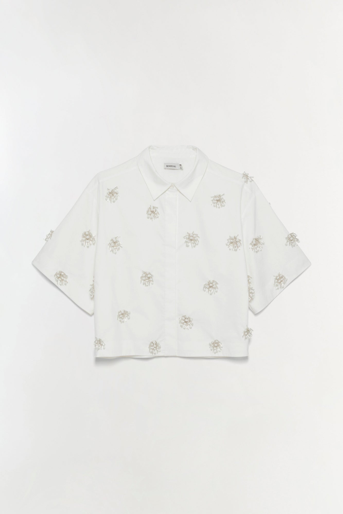 White camp shirt with scattered tan palm tree embellishments and short sleeves.