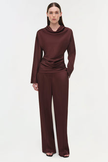Burgundy satin top with cowl neckline and ruched waist detail, long sleeves, paired with matching wide-leg trousers.