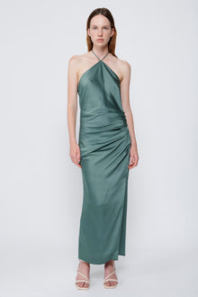 Sage green halter gown with ruched waist and asymmetrical draped neckline on model.