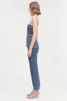 Woman wearing a sleeveless denim cargo top with side pockets, shown in profile view.