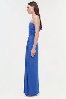 Woman wearing a strapless blue jersey gown with draped detailing at the waist and side, floor-length skirt.