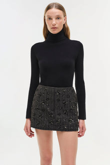 Black mini skirt with allover beaded and sequin embellishments paired with black turtleneck.