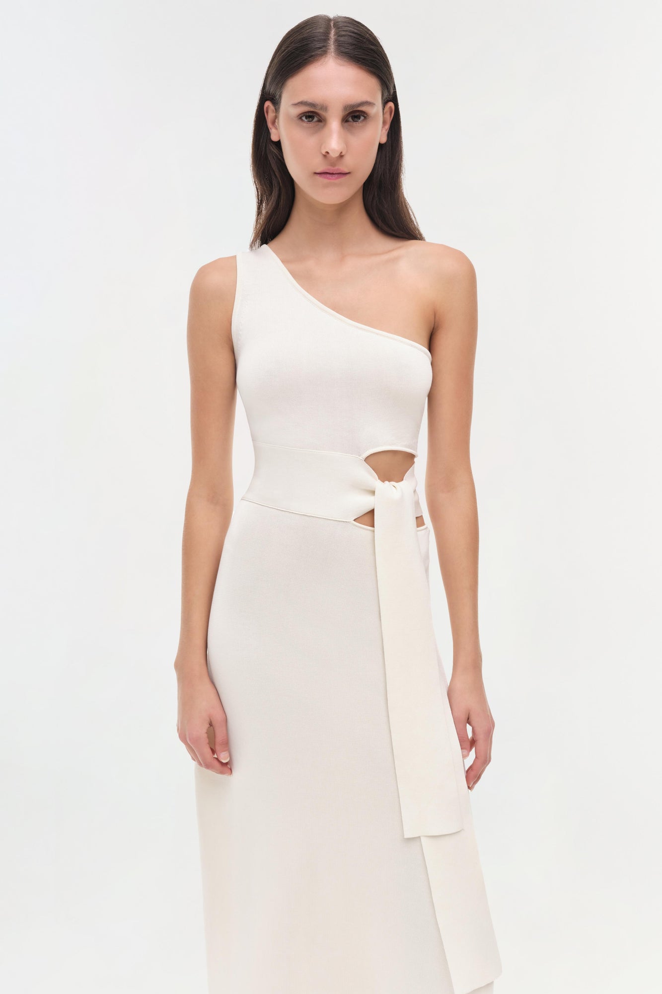 White one-shoulder dress with cutout waist detail and tied wrap belt.