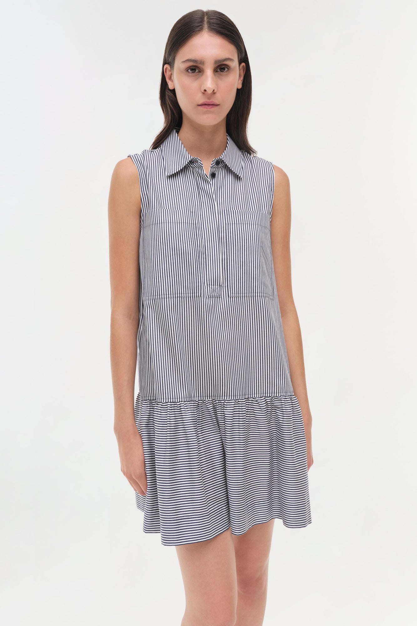 Sleeveless collared dress in navy and white vertical stripes with a striped gathered hem.