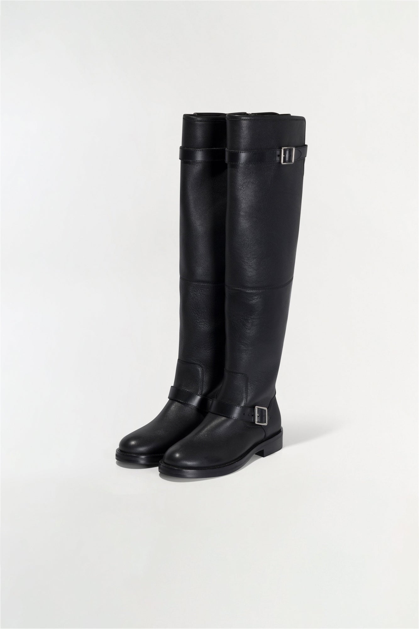 Black leather over-the-knee boots with buckle straps and flat soles.