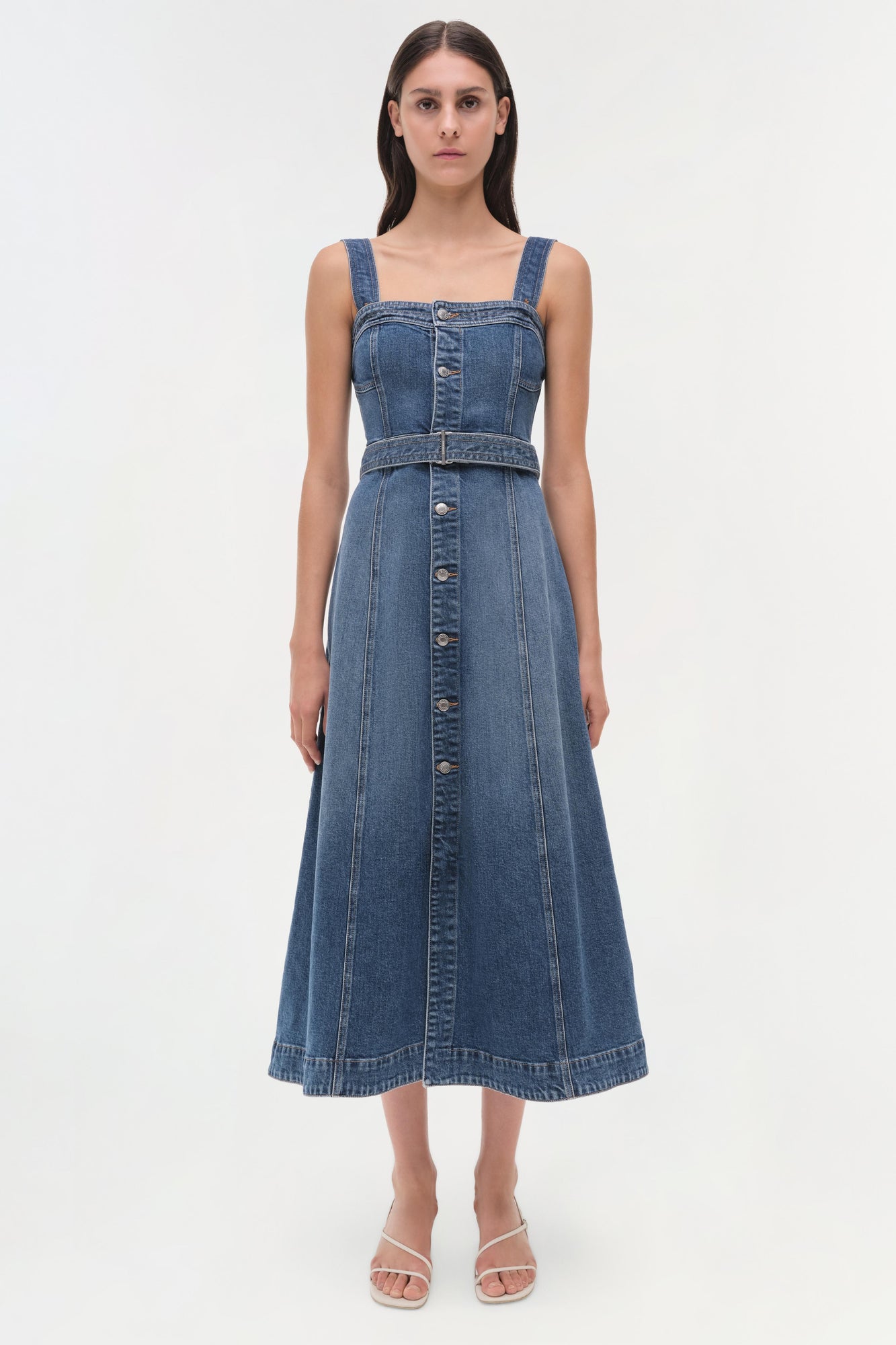 Blue denim sleeveless dress with square neckline, button front, and belted waist on a model.