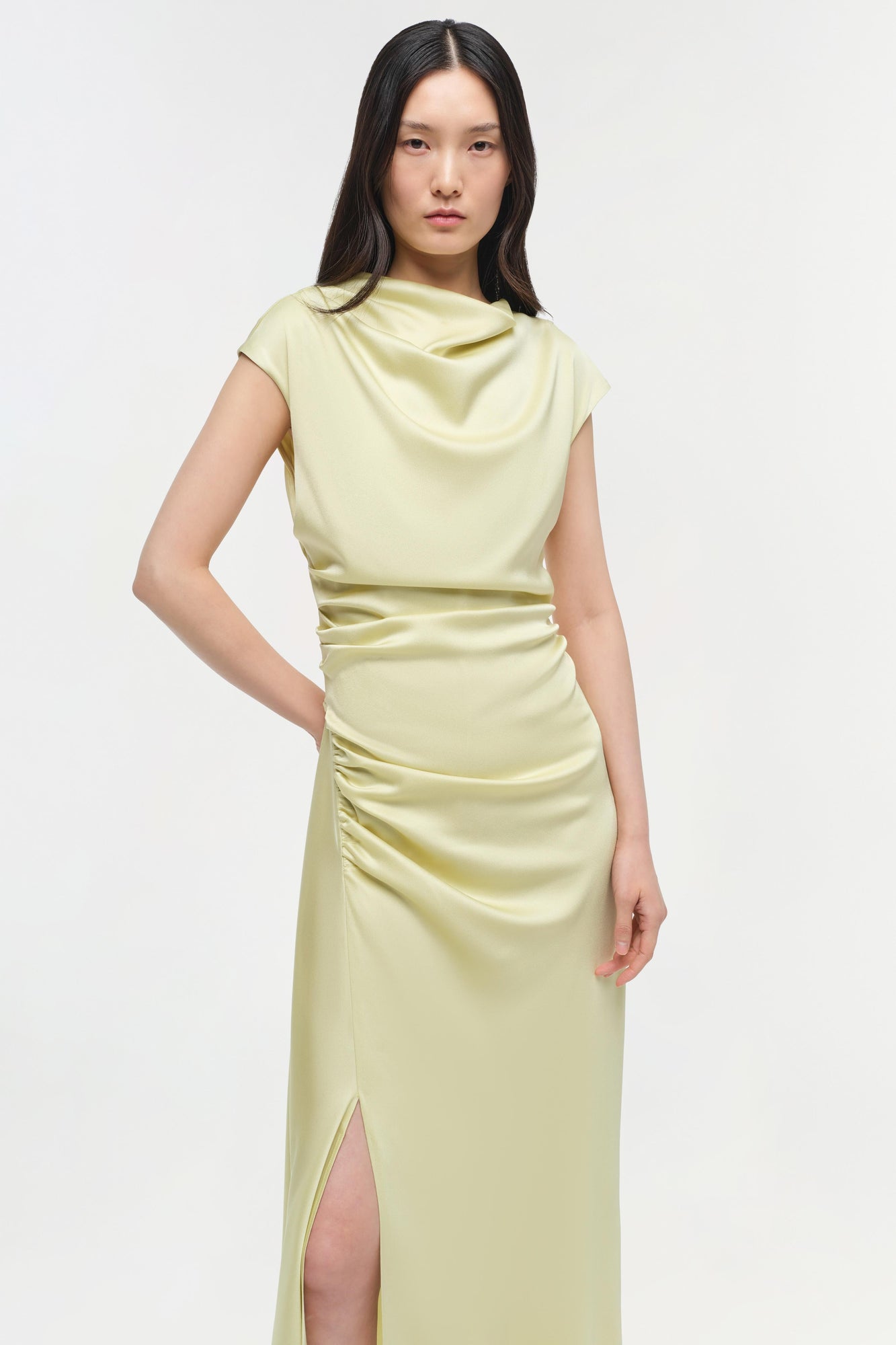 Pale yellow satin midi dress with draped cowl neckline, ruched waist, and front slit.