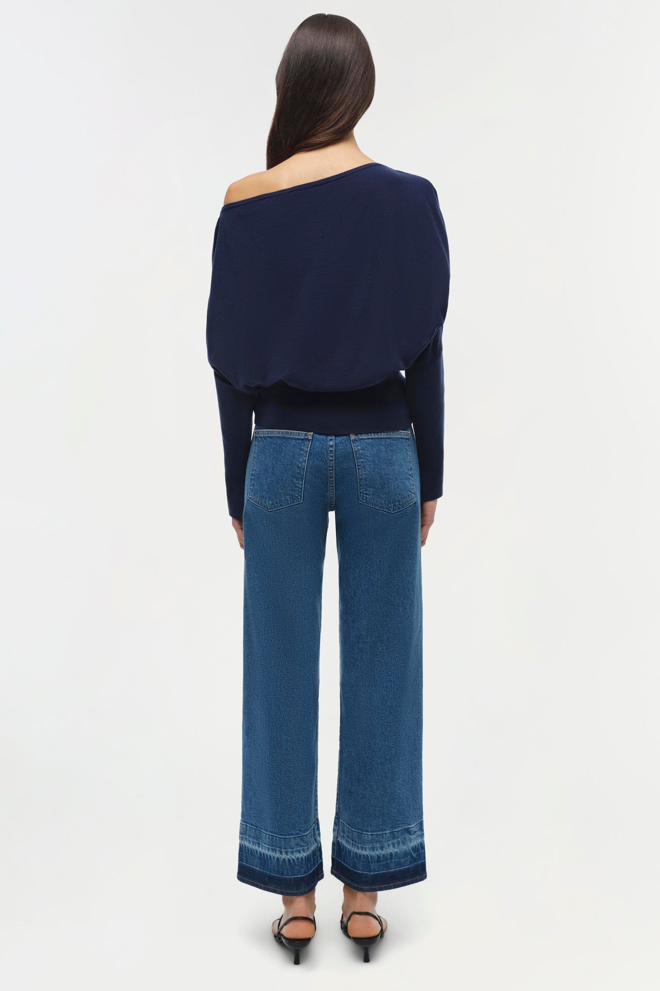 Navy blue off-shoulder cropped sweater with long sleeves worn with blue jeans.