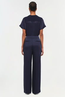 Back view of a person wearing a dark navy short-sleeve t-shirt with matching wide-leg trousers.