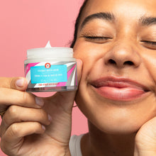 Model smiling and holding product next to her face. 