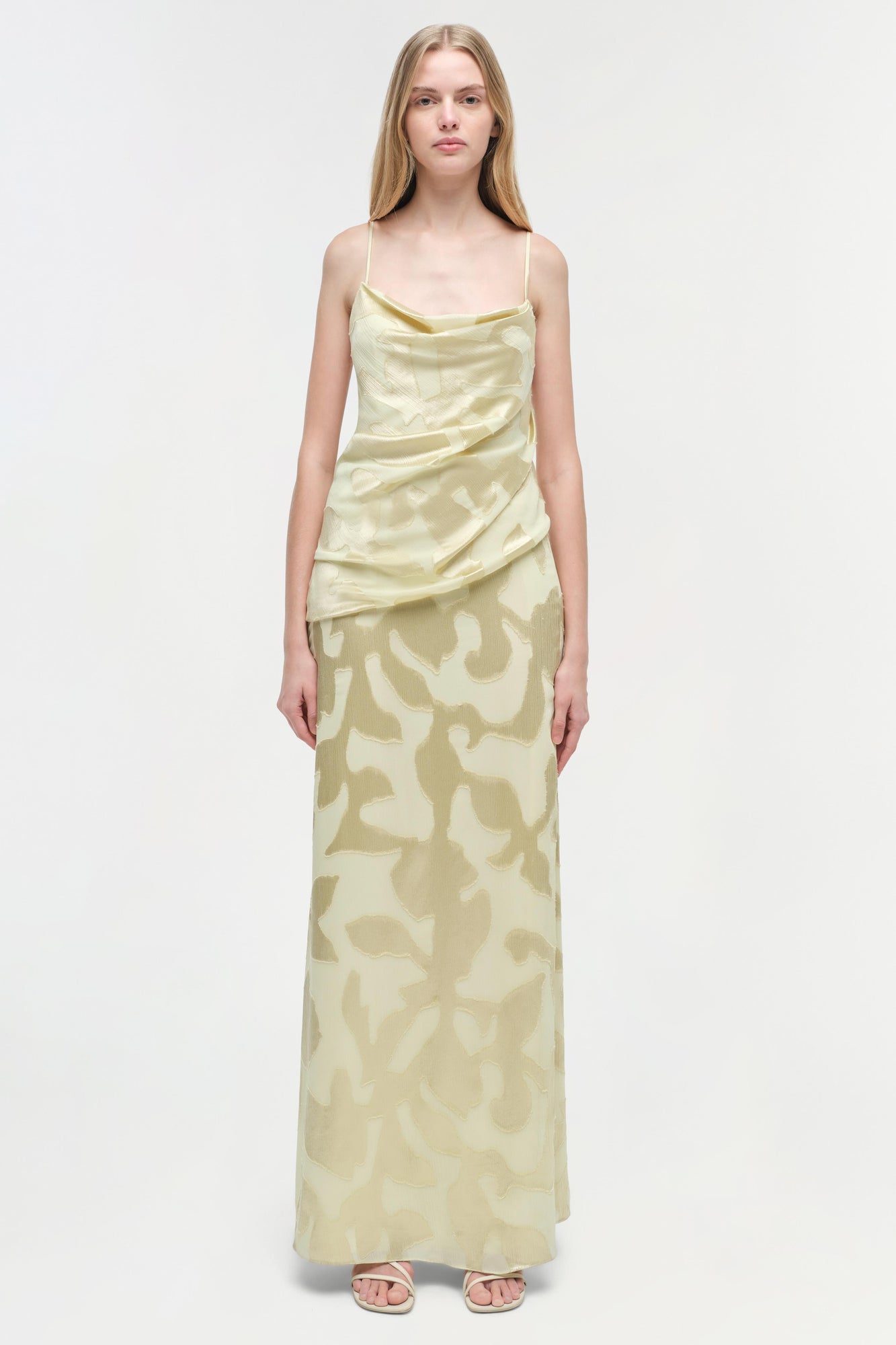 Pale yellow floor-length gown with abstract print, draped cowl neckline, thin straps, and ruched bodice detail.