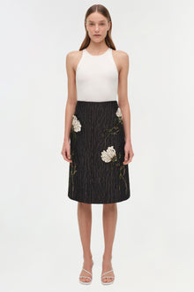 Black midi skirt with white floral jacquard pattern and embroidered details, paired with cream ribbed tank top.