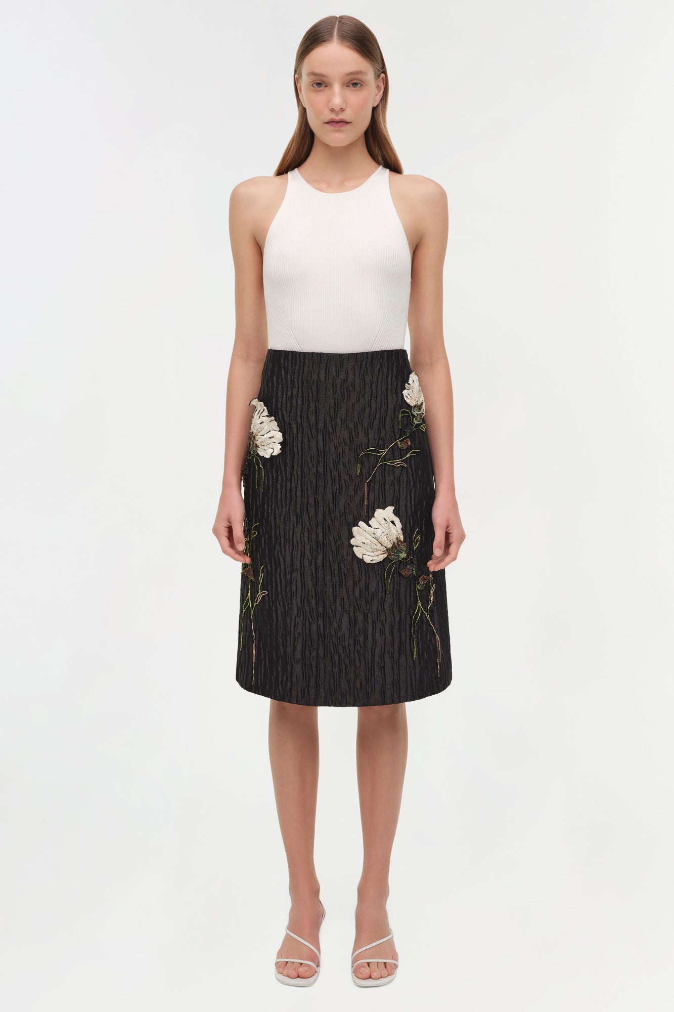 Black midi skirt with white floral jacquard pattern and embroidered details, paired with cream ribbed tank top.