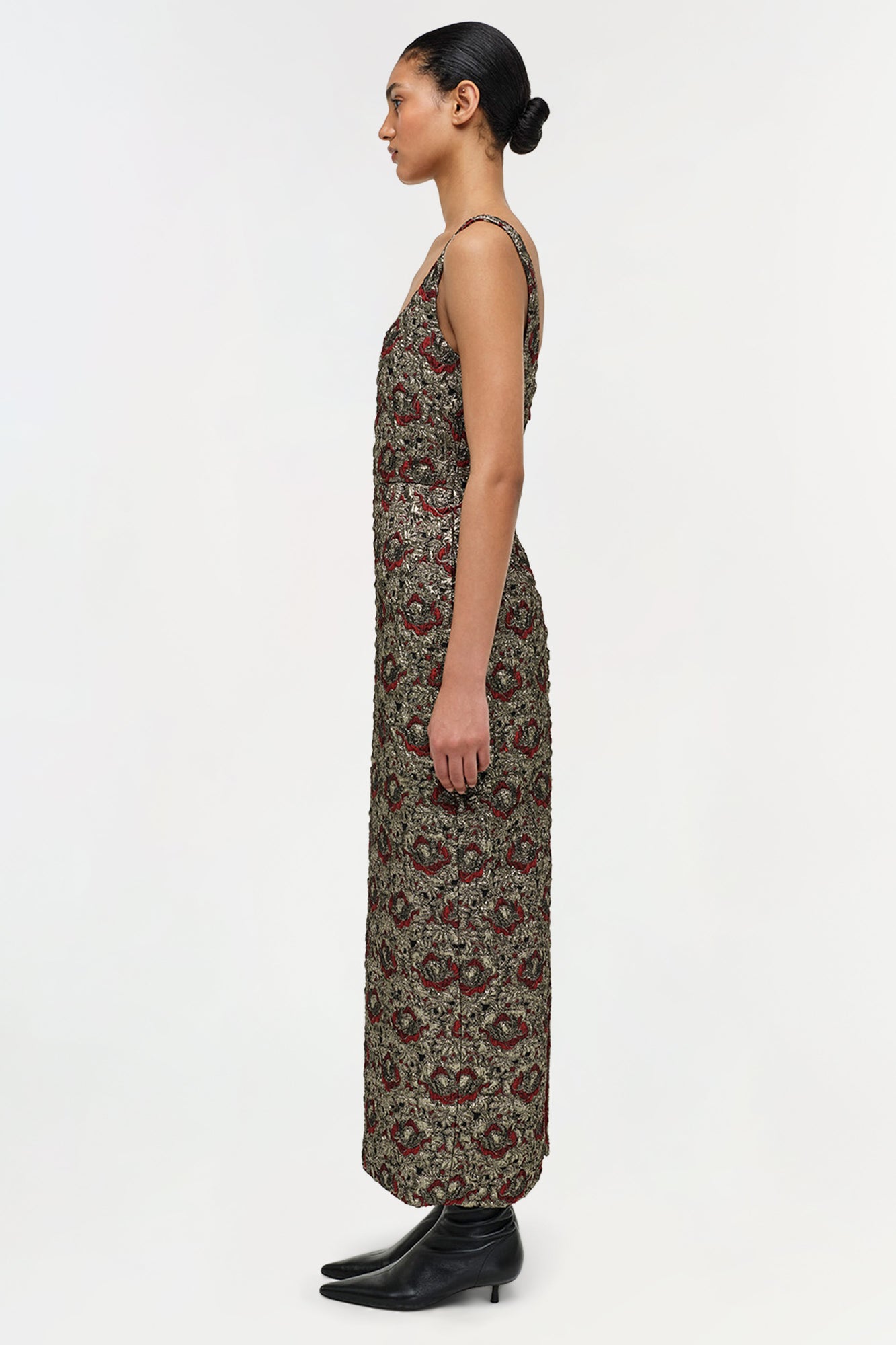 Sleeveless midi dress with gold and red jacquard pattern on sage green background, modeled with black kitten heels.