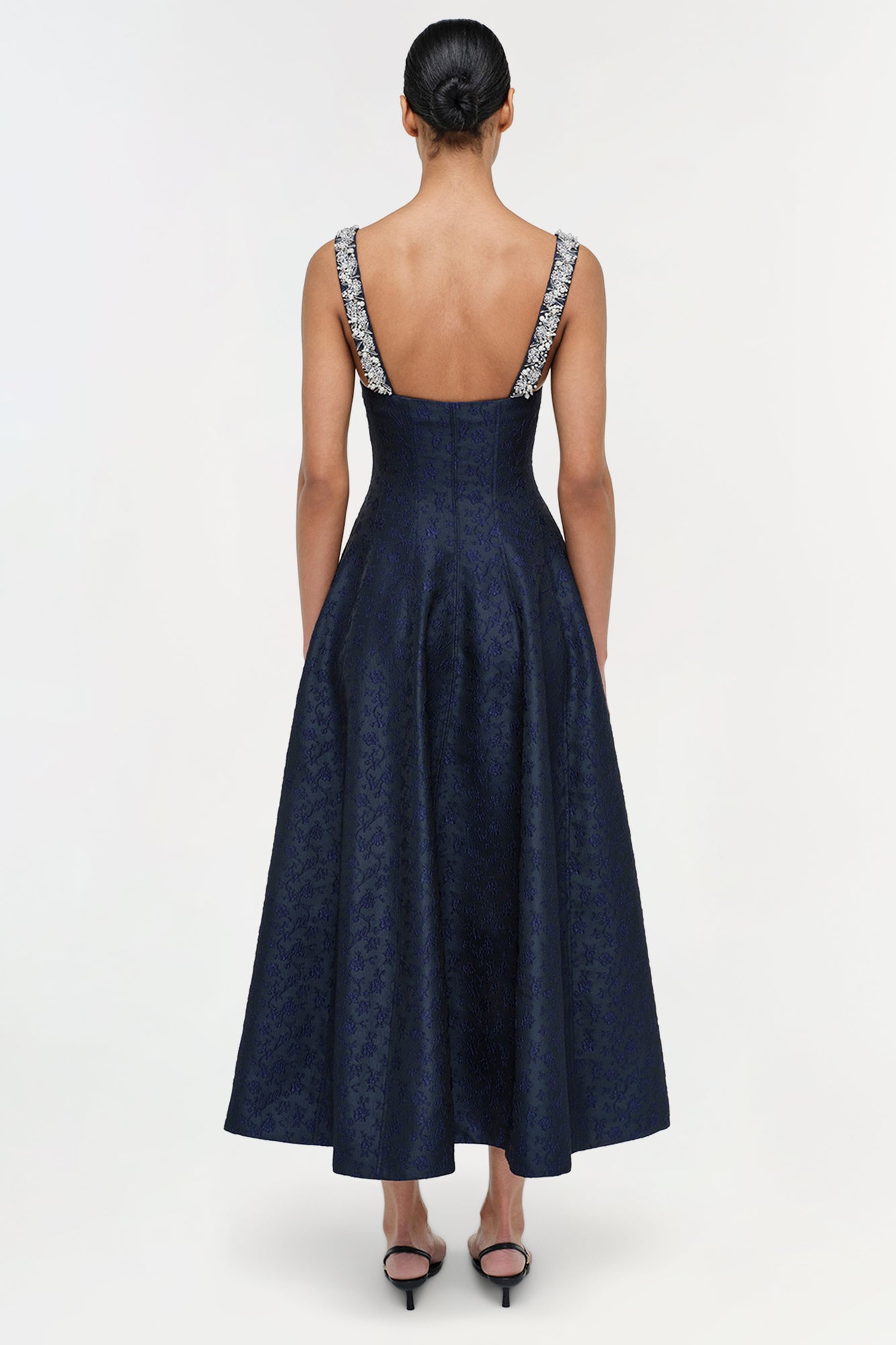 Navy jacquard midi dress with patterned straps and open back, shown on model from behind.