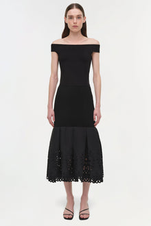 Black knit midi skirt with embroidered cutout hem detail, worn with off-shoulder top.