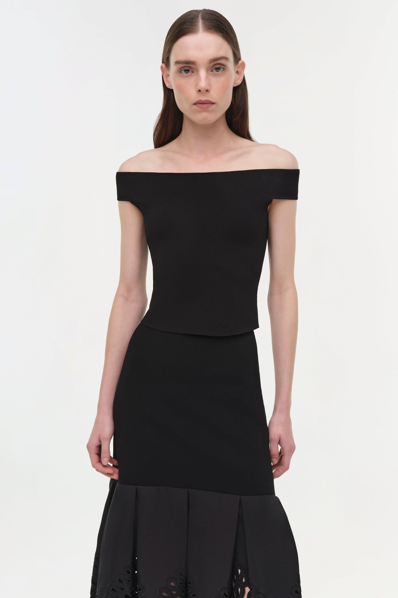 Black off-shoulder knit midi skirt with embroidered detailing at hem, worn with matching black top.