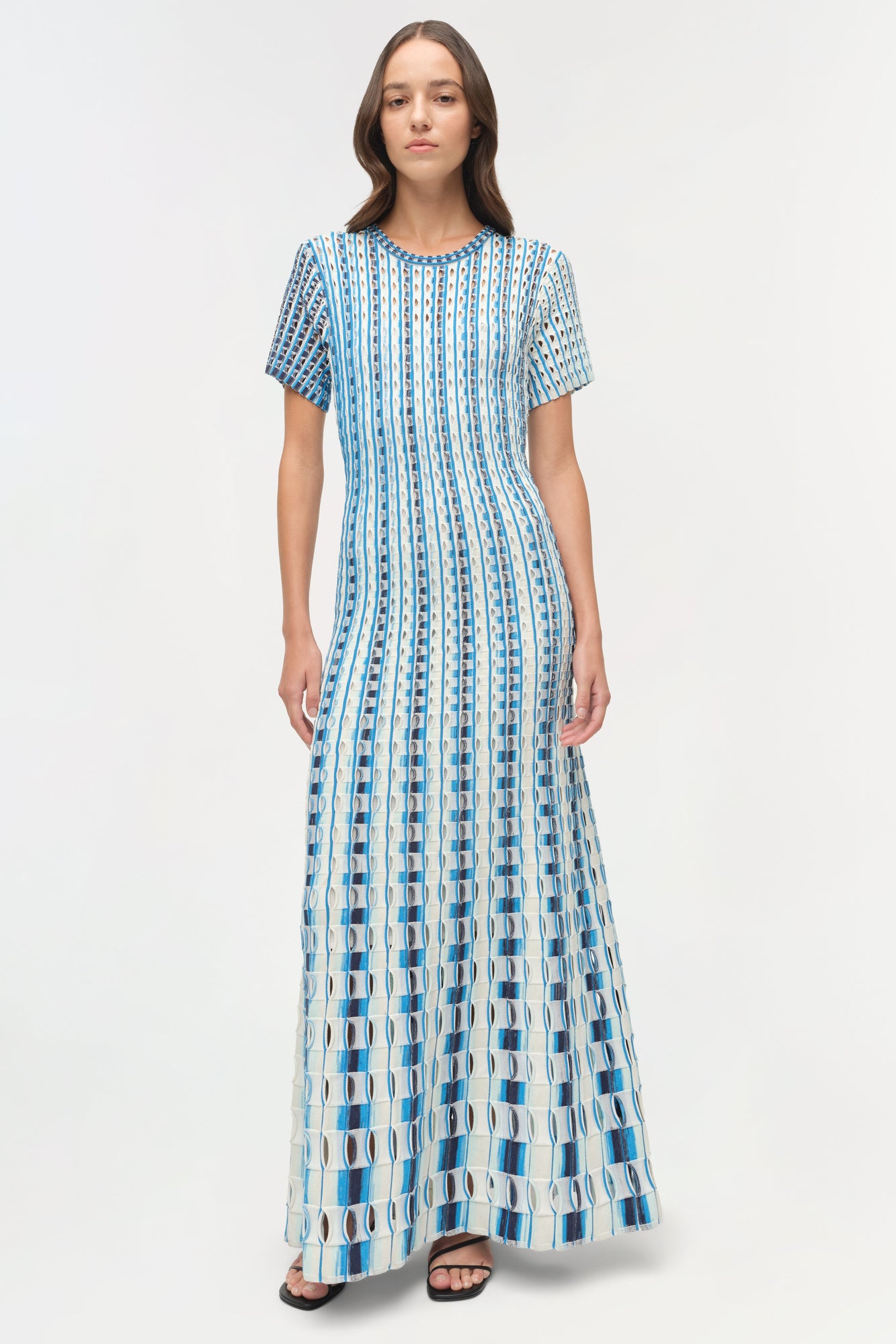 Blue and white knit midi dress with eyelet pattern and short sleeves on model wearing black sandals.