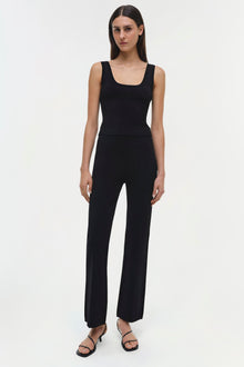 Woman wearing black sleeveless tank top with matching wide-leg pants and black strappy sandals.