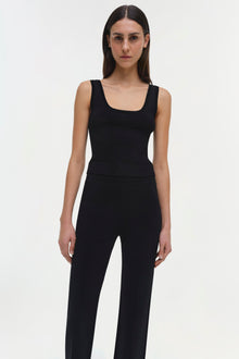 Black sleeveless tank top with square neckline on model wearing black pants.