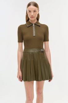 Olive green mini dress with ribbed knit short-sleeve top, polo collar with half-zip, and pleated skirt with belt detail.