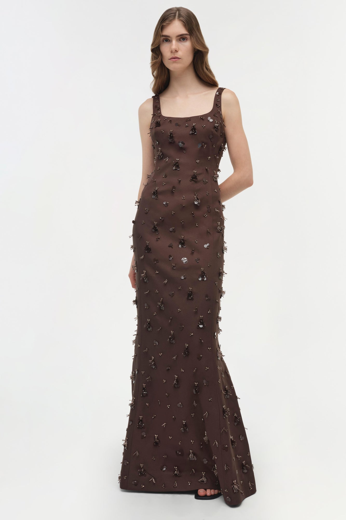 Brown sleeveless gown with scattered beaded and sequined embellishments throughout, fitted silhouette, floor-length.