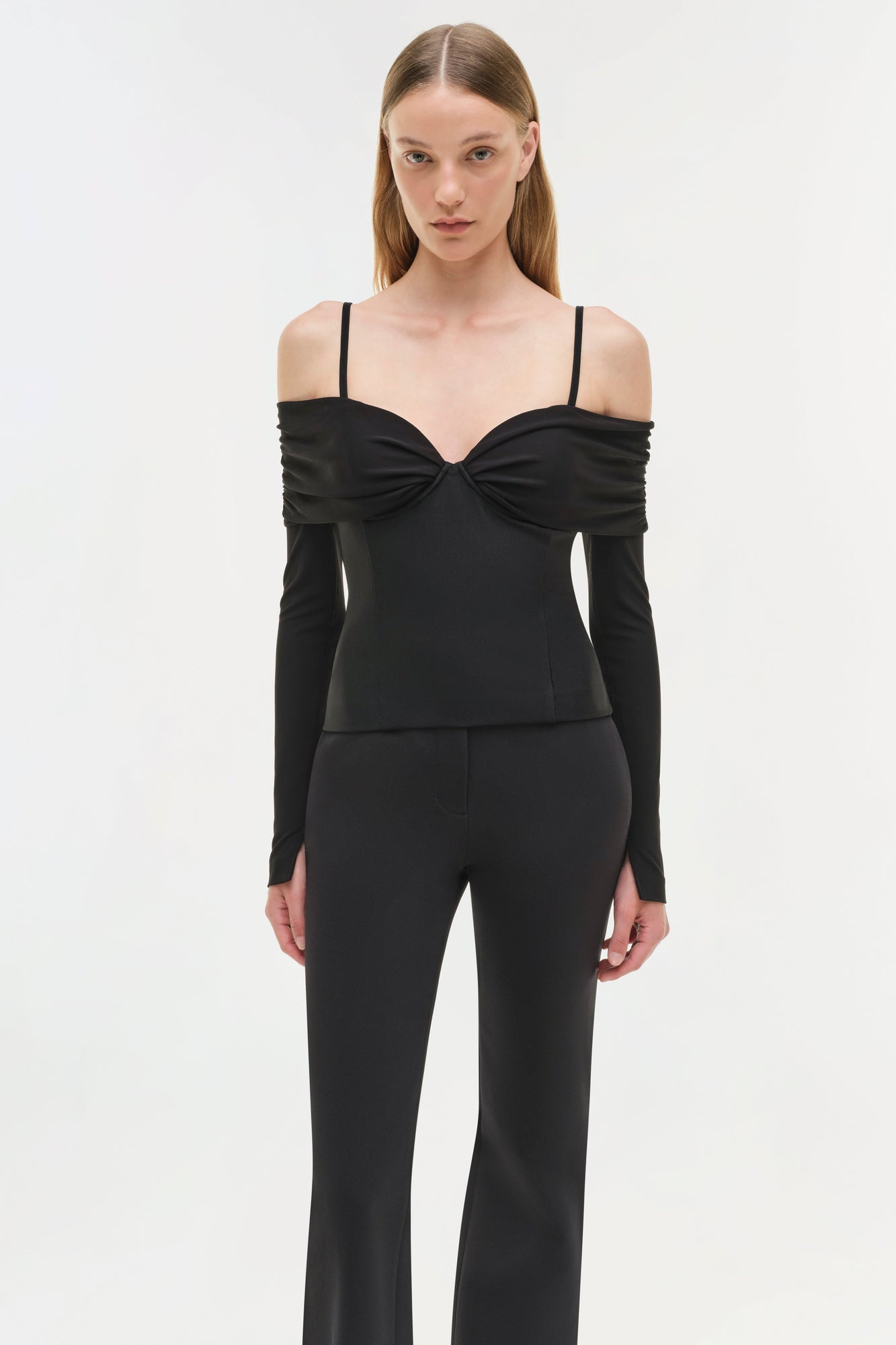 Black off-shoulder top with long sleeves, twisted neckline detail, and thin shoulder straps.
