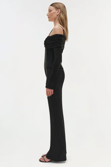 Black off-shoulder top with ruched neckline and long sleeves, shown on model in side profile.