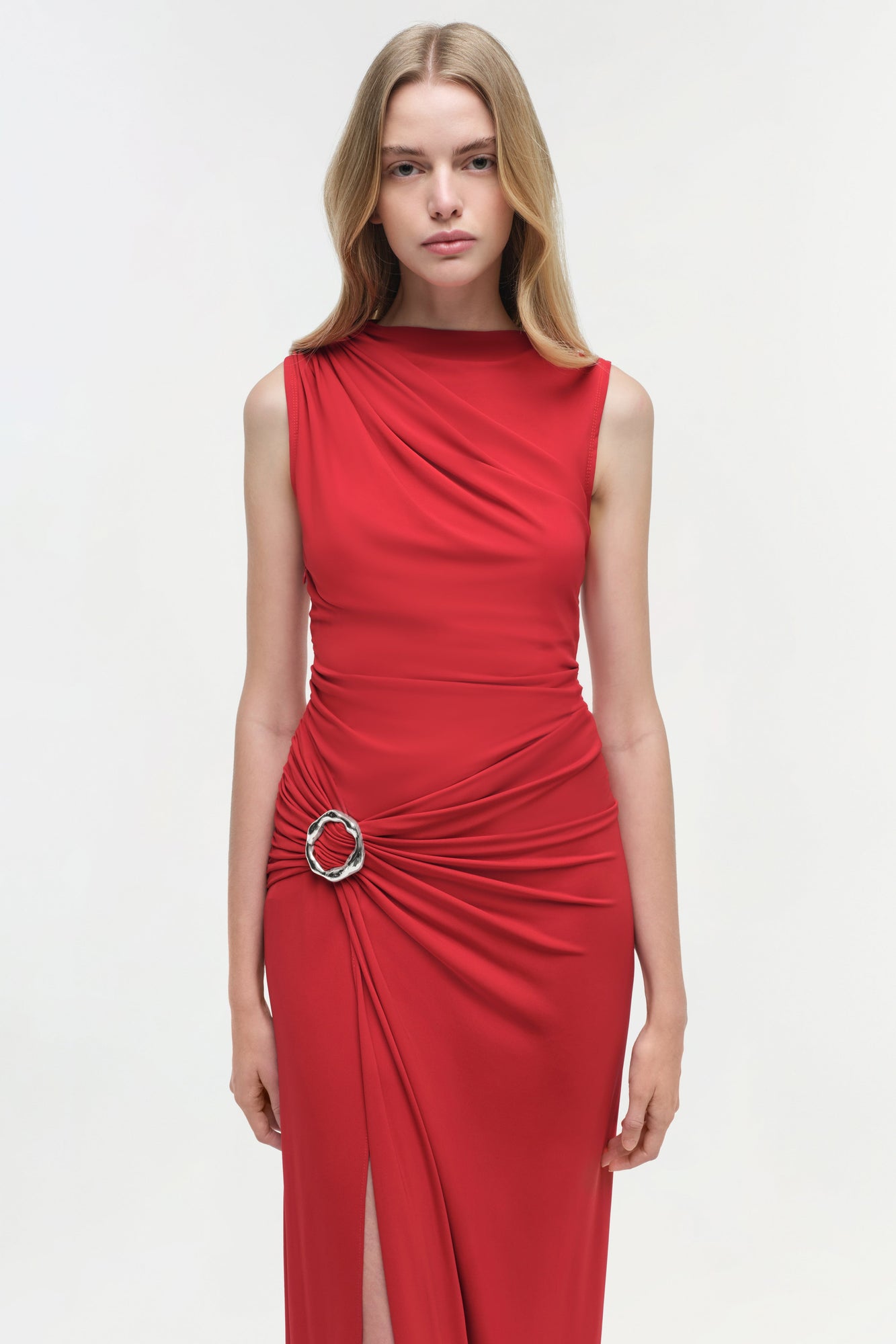 Red sleeveless jersey gown with ruched waist detail and decorative ring buckle accent.
