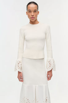 Cream knit midi skirt with eyelet embroidered hem and pleated bottom, paired with matching long-sleeve top.