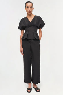 Black cotton faille top with V-neckline, short puffed sleeves, and structured peplum waist detail.