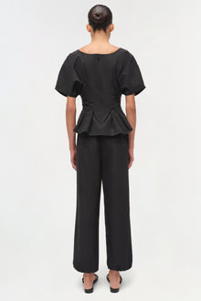 Black cotton top with short puffed sleeves and ruched peplum waist, shown from back view.