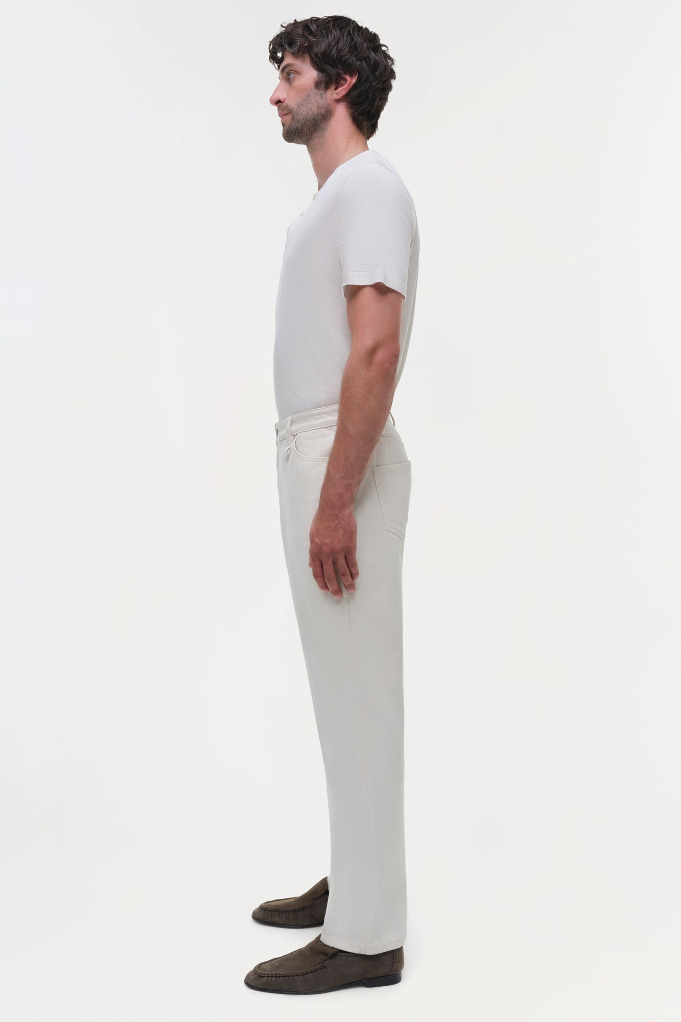 Man wearing white wide-leg jeans with a white t-shirt, shown in side profile.