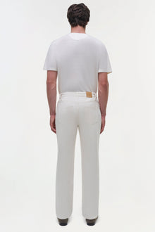 Man wearing cream-colored wide leg jeans with brown leather patch and matching short-sleeve shirt, back view.