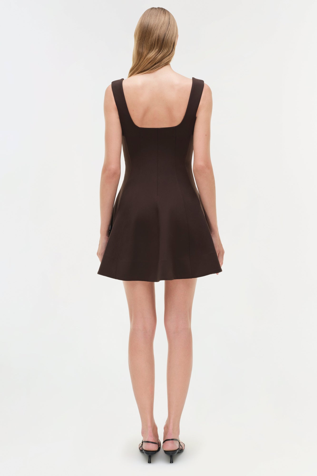 Black sleeveless mini dress with square neckline and fit-and-flare silhouette, shown on model from back view.