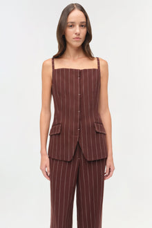 Woman wearing burgundy pinstriped suiting pants with matching sleeveless vest featuring front pockets.