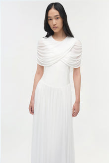 White jersey maxi dress with draped cape collar and pleated skirt.