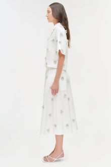 White camp shirt and midi skirt set with silver beaded embellishments throughout, shown on model in side profile.