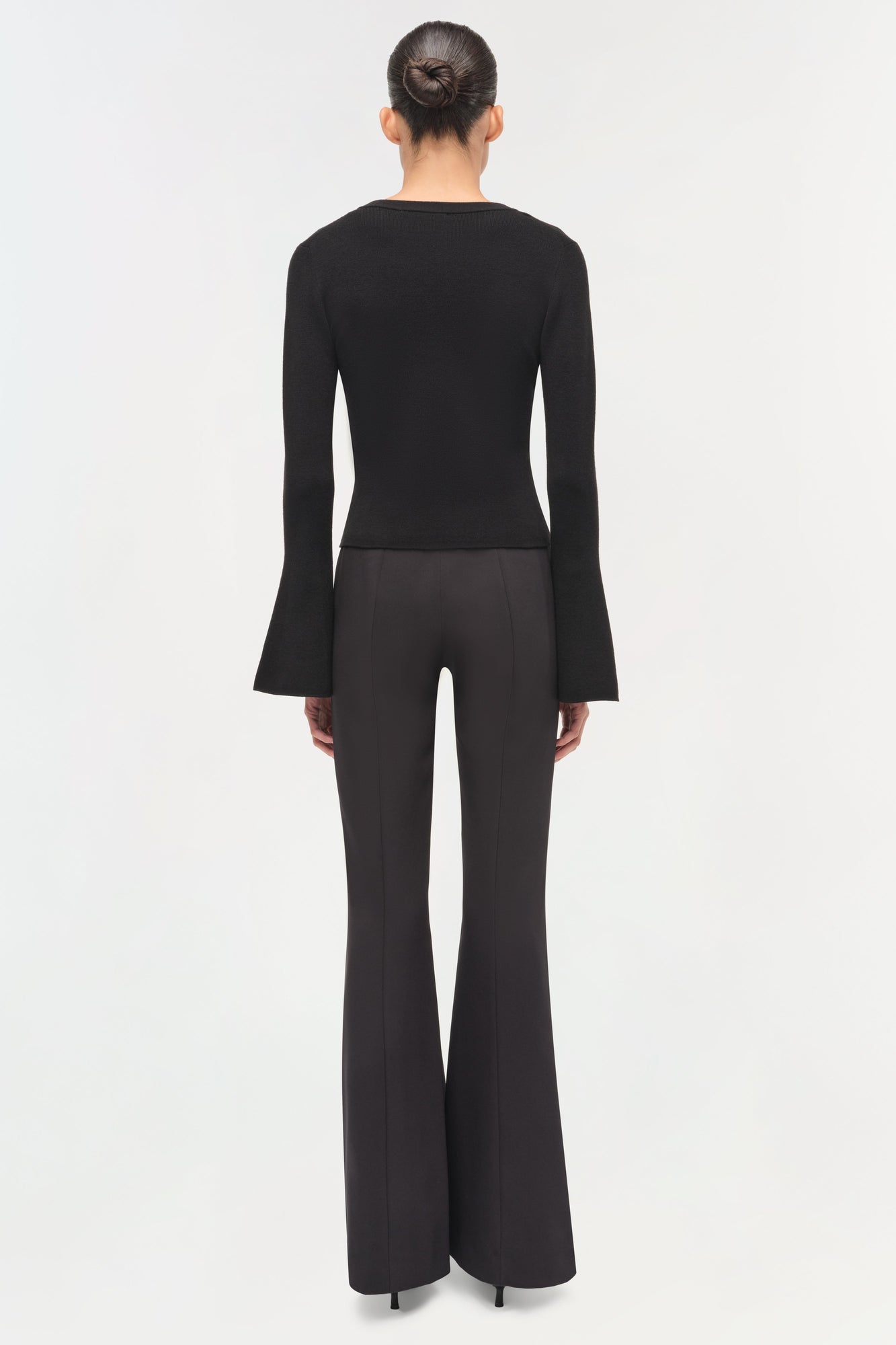 Black wool top with flared long sleeves, shown from back on model wearing black pants.
