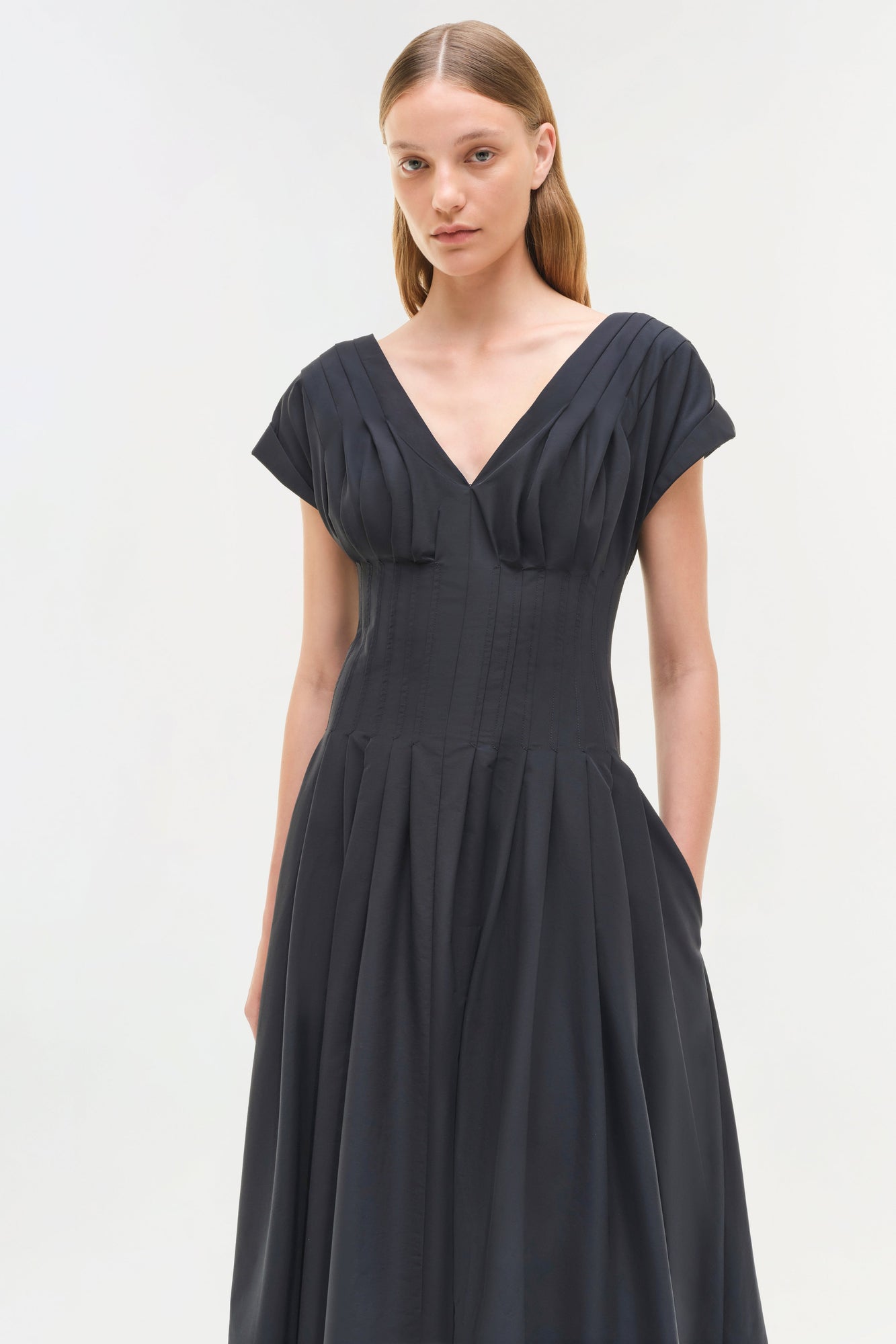 Black cotton midi dress with short sleeves, V-neckline, and pleated bodice and skirt.