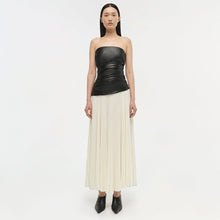 Strapless dress with black leather bodice and ruched waist, cream pleated skirt, worn with black ankle boots.