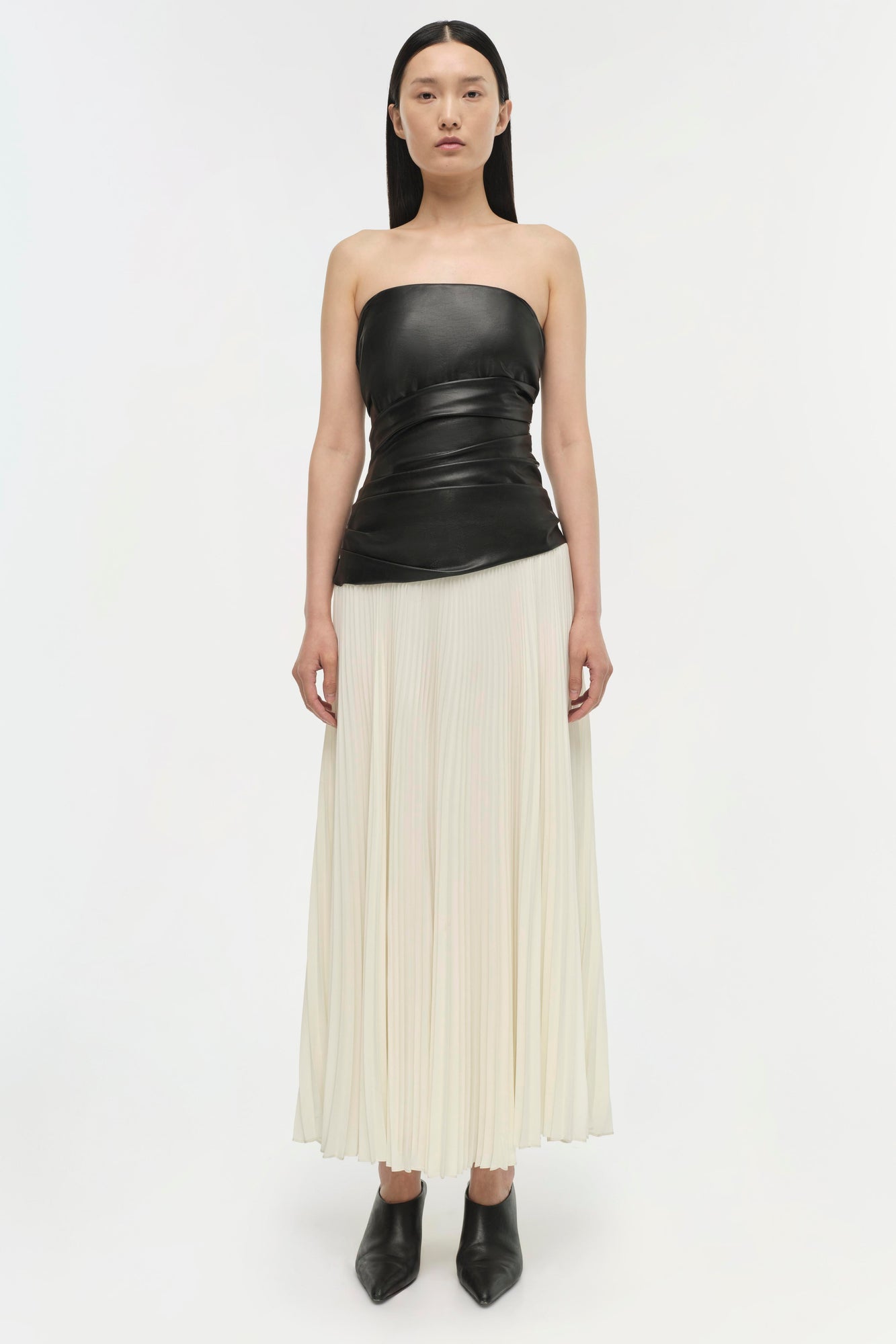 Black leather strapless top with ruched waist paired with cream pleated skirt.