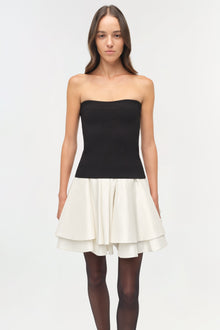 Black knit strapless top with white pleated taffeta skirt, modeled with dark tights.