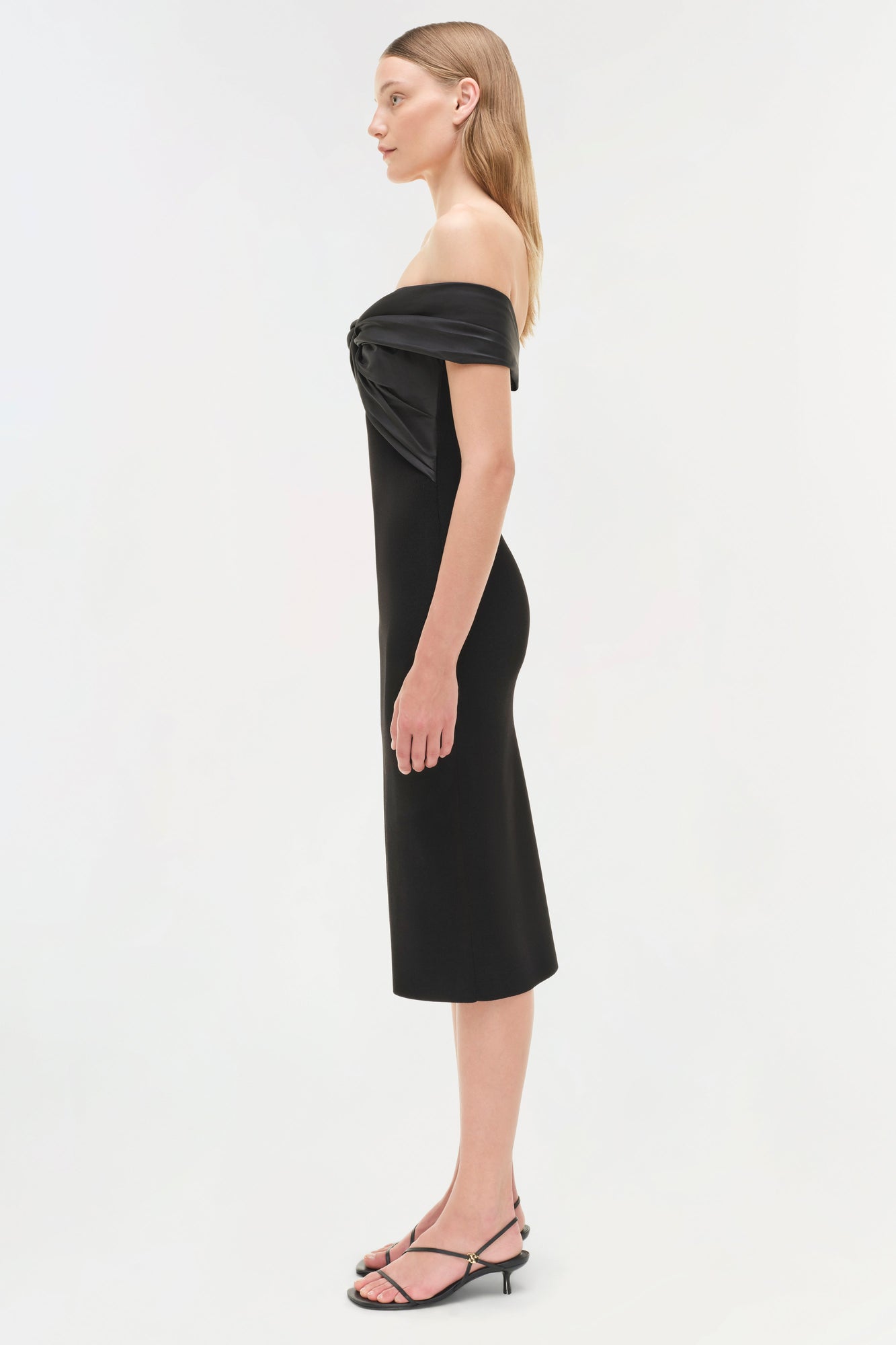 Black off-shoulder midi dress with draped neckline, fitted bodice, and knee-length skirt on model.