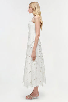 White sleeveless midi dress with floral embroidered cutout pattern, shown on model in side profile view.