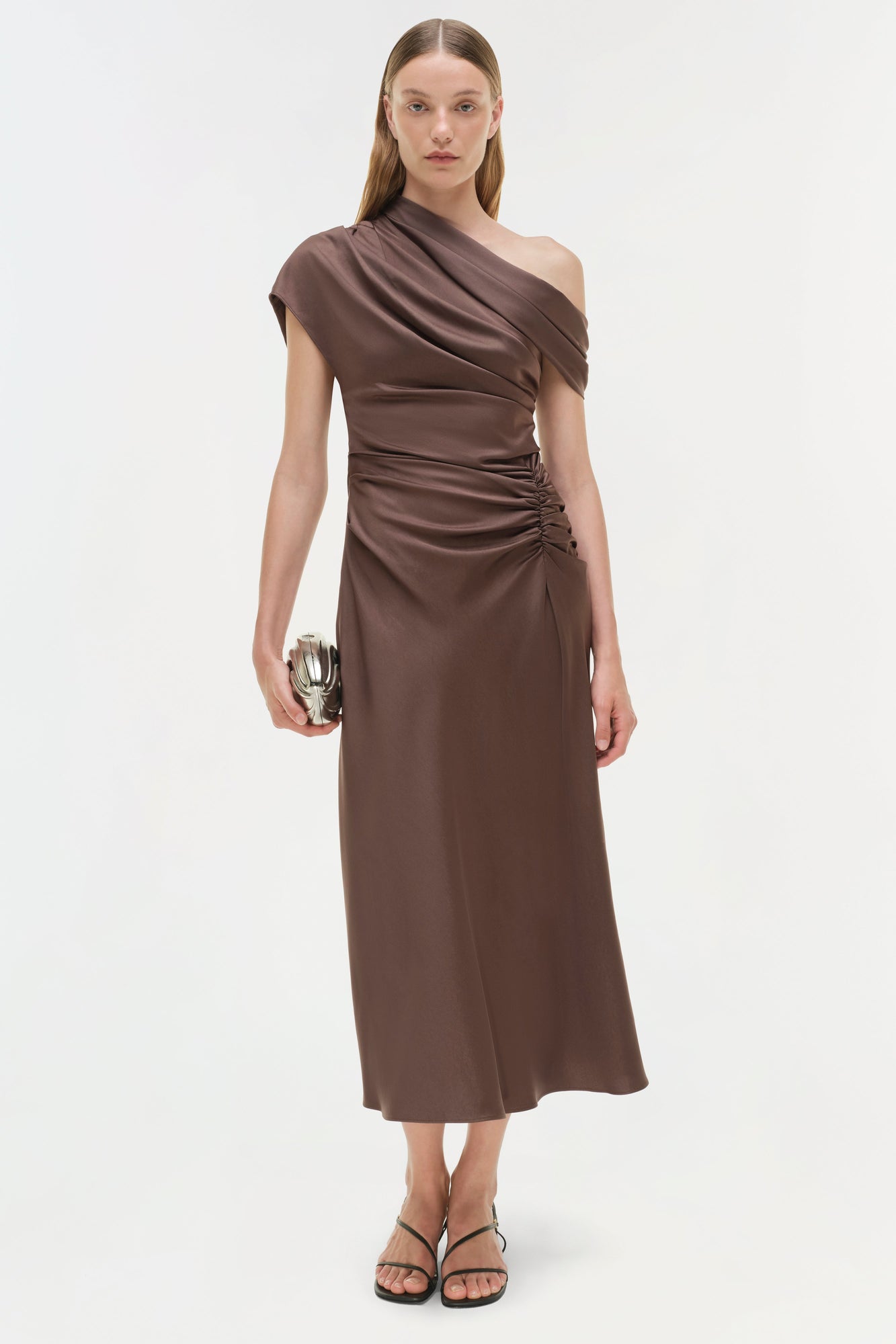 Brown satin midi dress with asymmetrical neckline and ruched side detail, worn with black sandals.