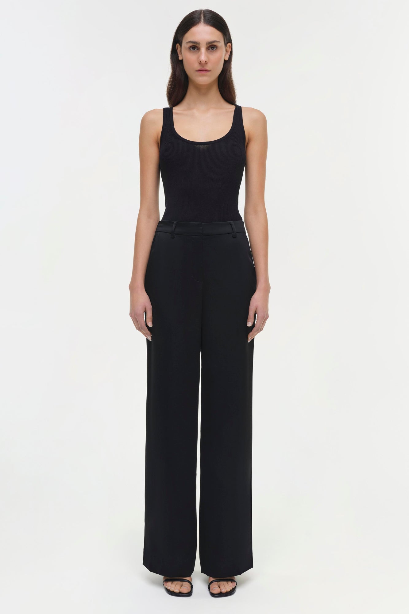 Woman wearing black Tavar pants with high waist and wide legs, paired with a black ribbed tank top.