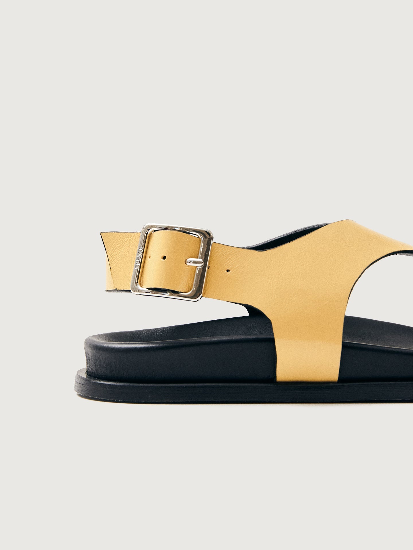Buttery yellow colored sandal with black sole and silver hardware. 